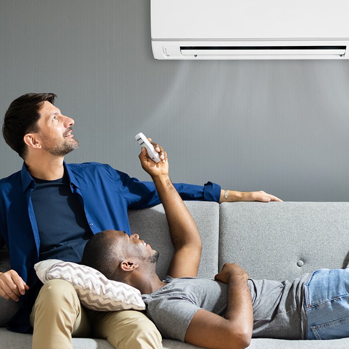 man turning on air conditioner using remote control