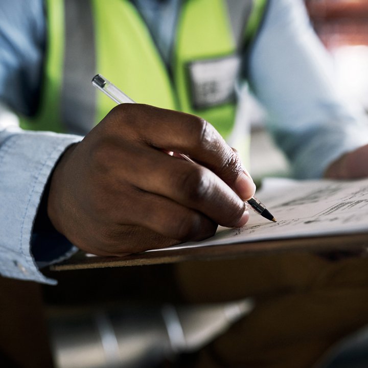 Man with high visibility vest writing on a paper